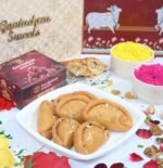 Gujiya served on silver thali with rose petals and crushed pistachios
