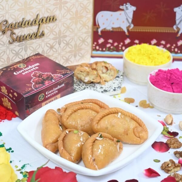 Gujiya served on silver thali with rose petals and crushed pistachios
