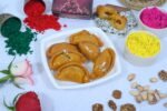 Gujiya arranged on a silver platter with festive decorations.